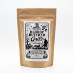 A kraft paper stand-up pouch of Marsh Hen Mill 'Bloody Butcher Grits' with a large white label featuring a black Halloween-themed illustration, photographed on a clean white background.