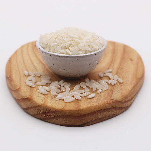 Ceramic bowl of Carolina gold rice on round wooden plank